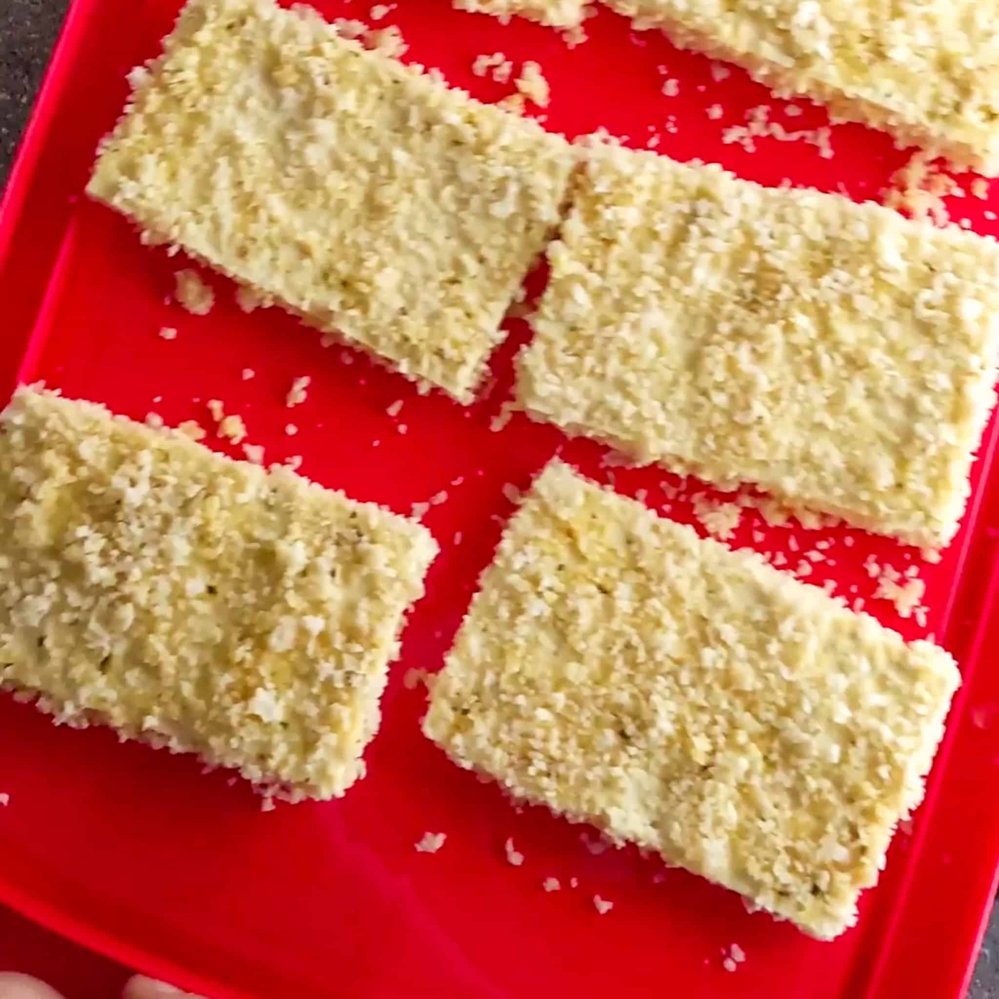 6 breaded large tofu slices laid in two rows on a flat container