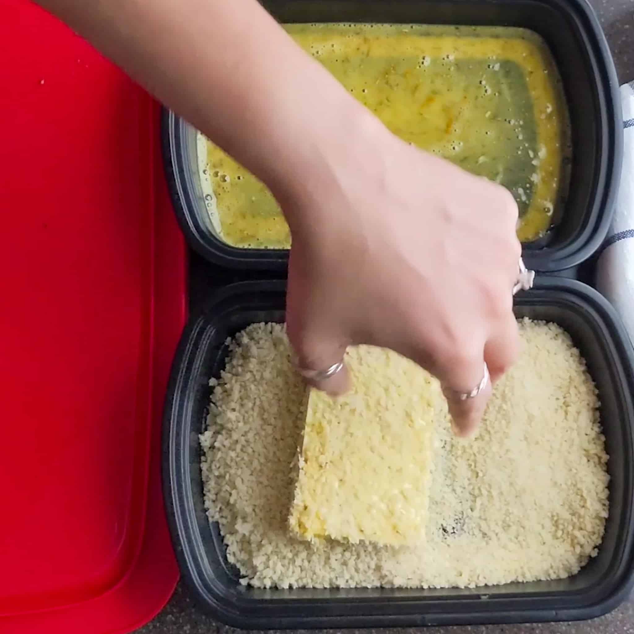 egg dipped large sliced tofu covered in japanese panko in a shallow container filled with more panko.