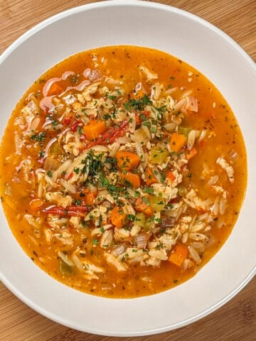 top view and close up the Lemon Calabrian Chili Chicken Orzo Soup in a wide rim bowl .
