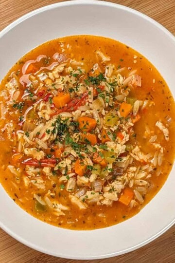 top view and close up the Lemon Calabrian Chili Chicken Orzo Soup in a wide rim bowl .