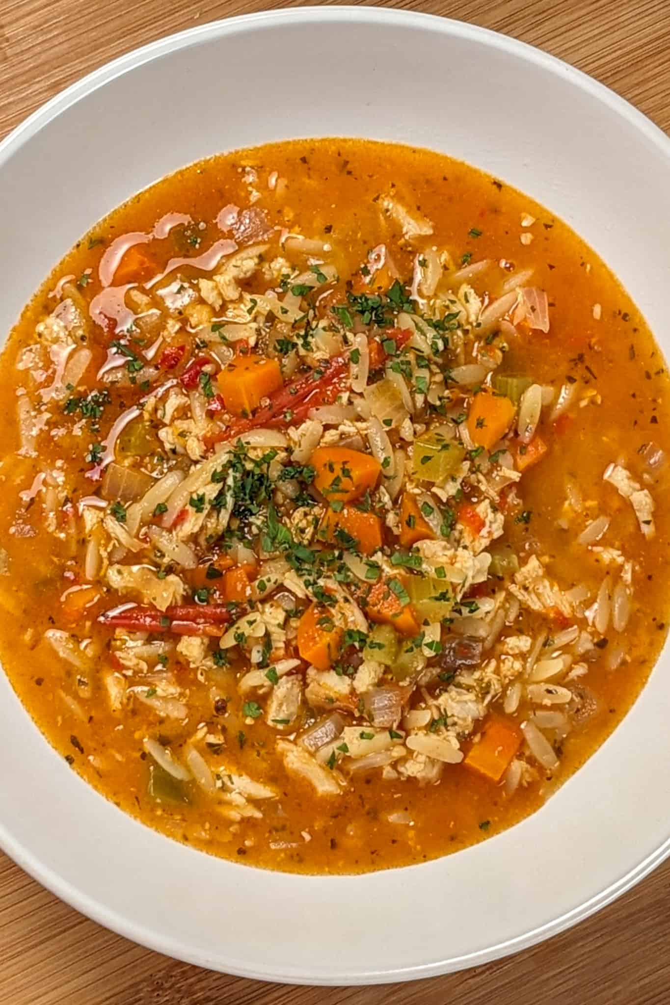 top view and close up the Lemon Calabrian Chili Chicken Orzo Soup in a wide rim bowl.