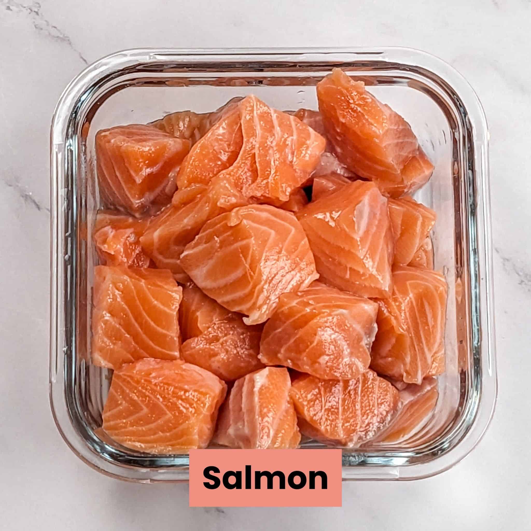 raw salmon cut into large chunks in a square glass container