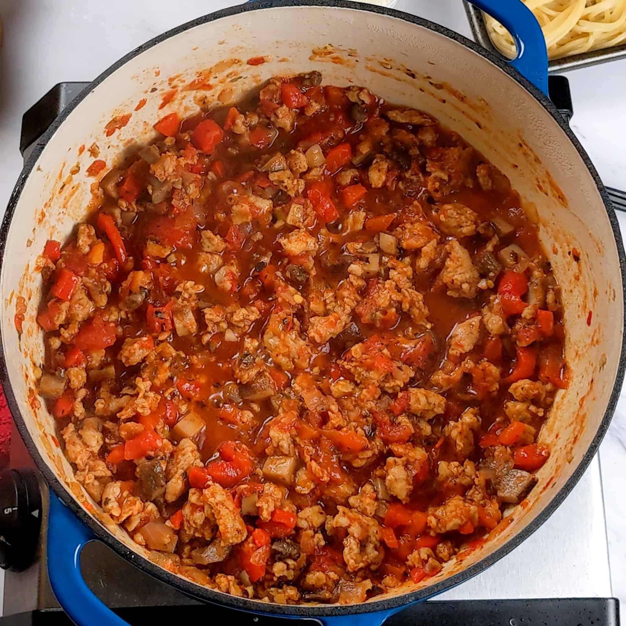 tomato sauce coated cooked crumbled sweet italian chicken sausage with diced portobello mushrooms and onions in a pot