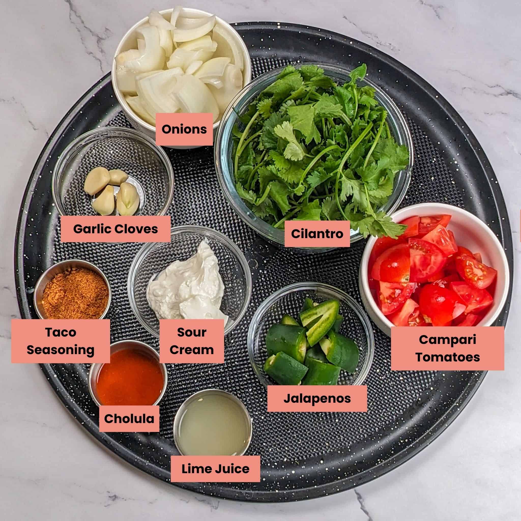 ingredients for the Easy Spicy Crispy Chicken Tacos with Cholula Sour Cream in containers on a large round pizza pan.