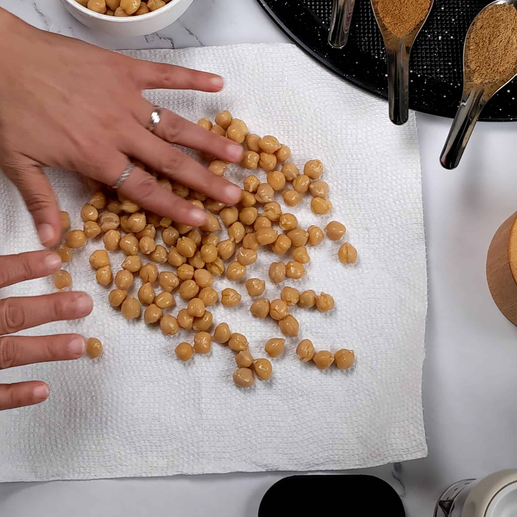 hands spreading out chickpeas on a paper towel.