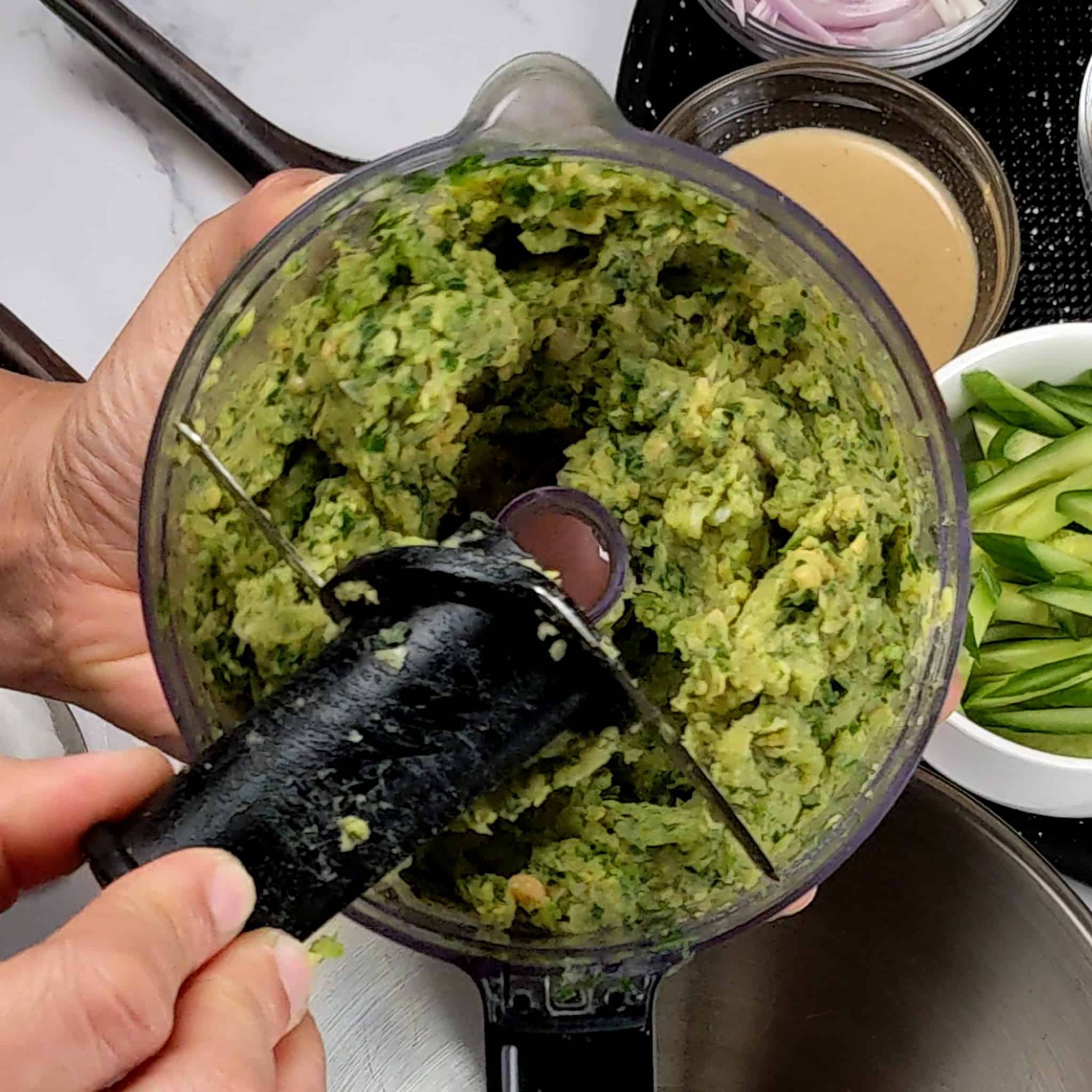 blended chickpea herb mixture in a food processor with the blade being taken out.