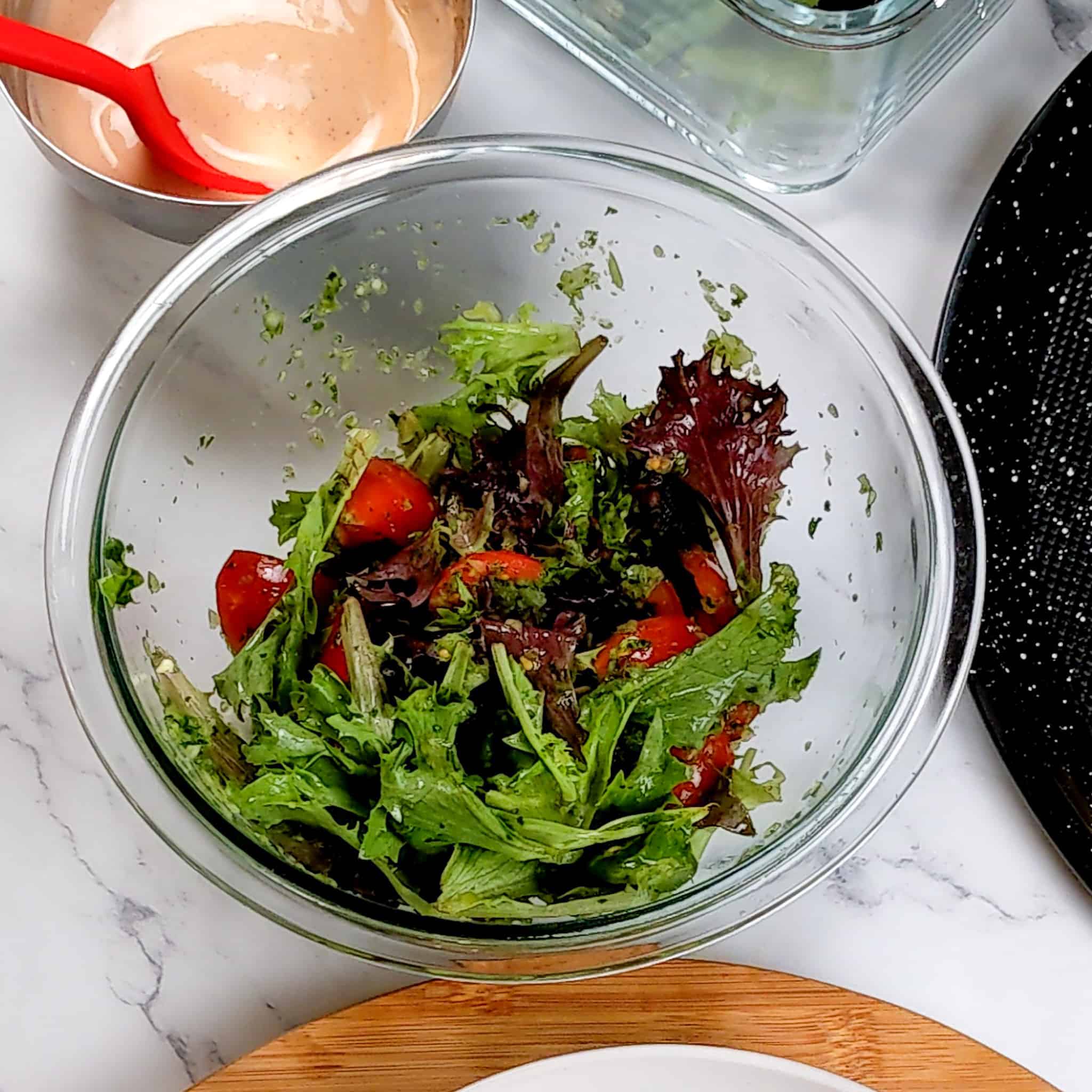 tomato and mixed green salad in a glass mixing bowl