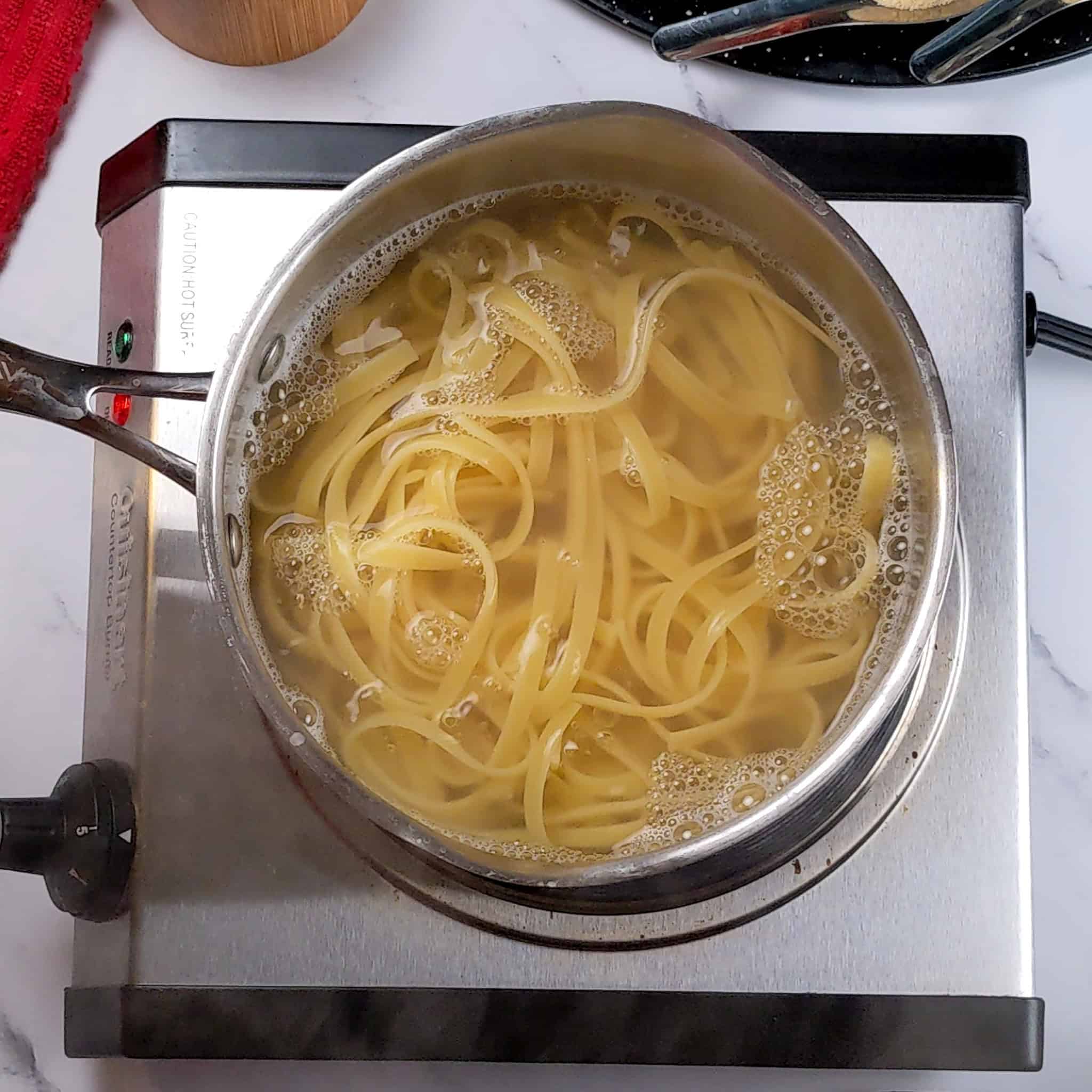fettuccini pasta boiling in a pasta pot.
