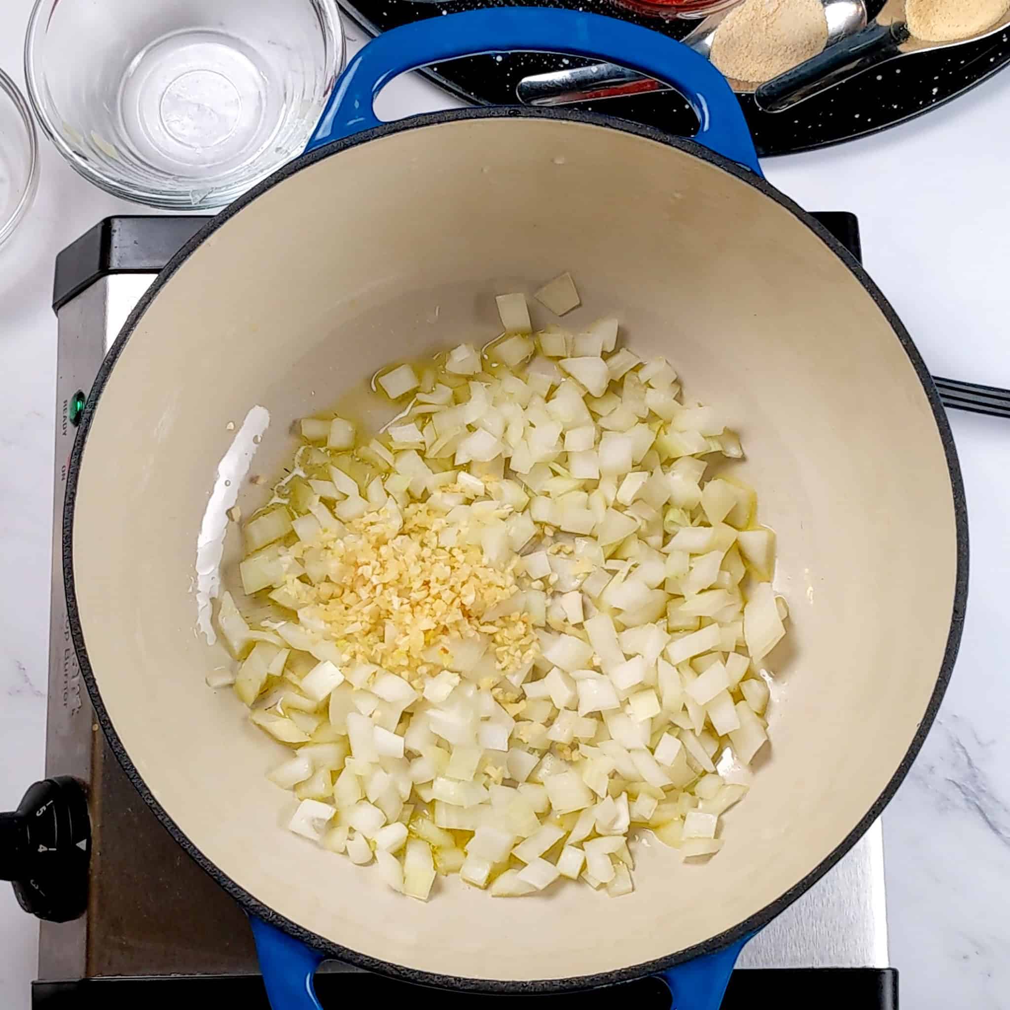 chopped onion and garlic cooking in oil in a lodge Dutch oven.