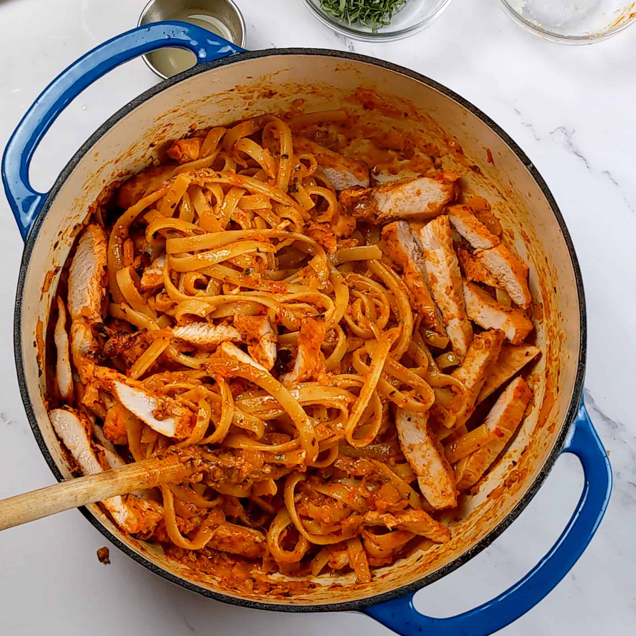 chili garlic sauce pasta sauce soaked fettuccini pasta in a dutch oven with sliced chicken.