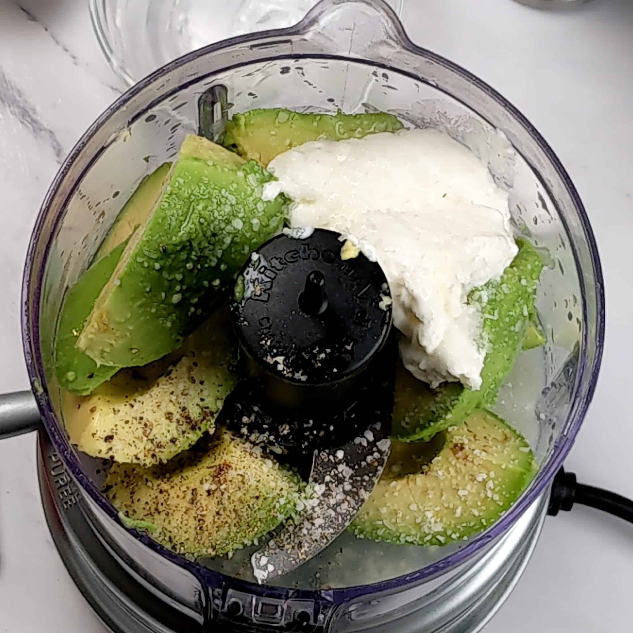 large chunks of ripe avocado, sour cream, salt and pepper in an open food processor.