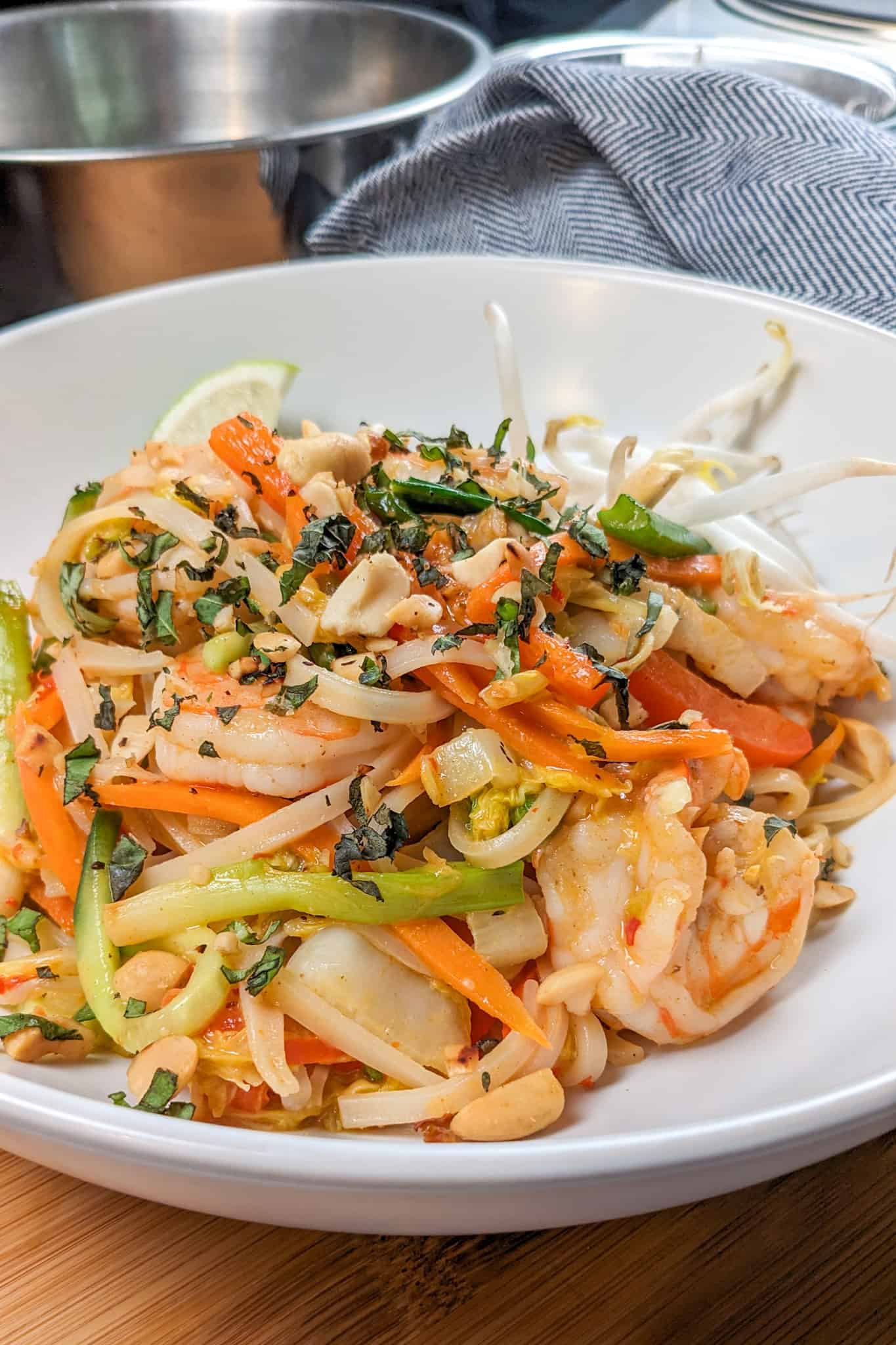 side view of the Shrimp and Pork Belly Pad Thai - Spring Roll Style in a wide rim bowl.