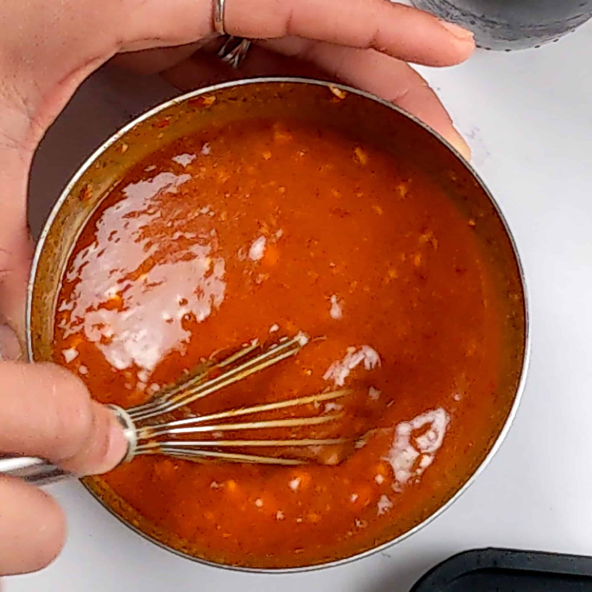 The garlic chili peanut sauce being whisked in a small stainless steel bowl.