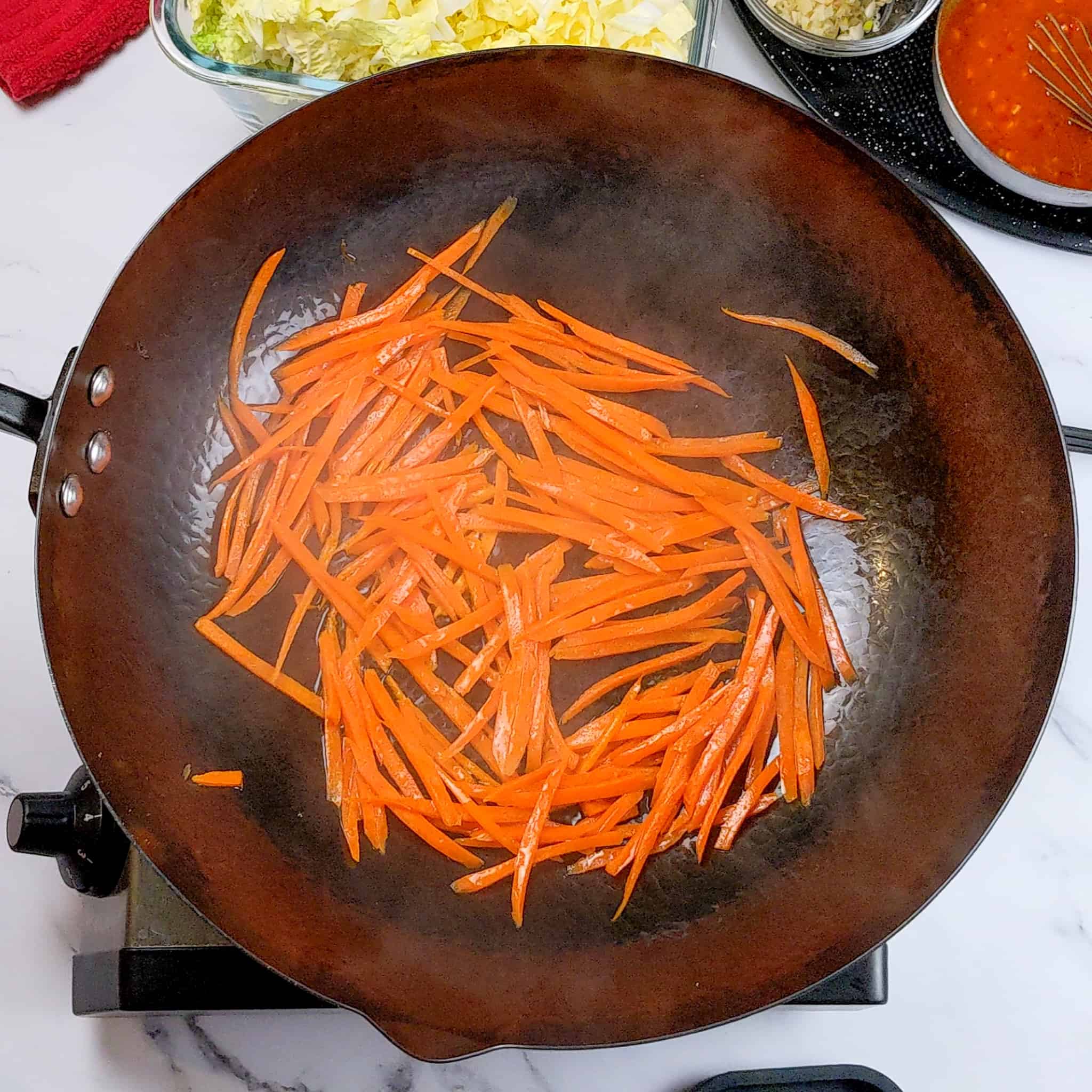 carrots in thin strips stir-frying in a wok.