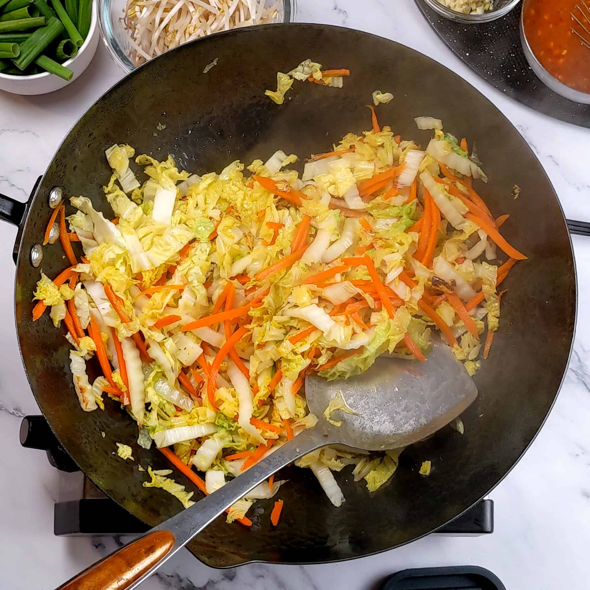 nappa cabbage and carrots in thin strips stir-frying in a wok.