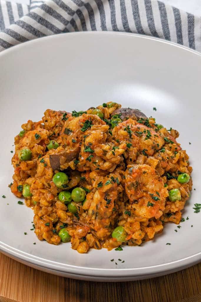 The Spicy Shrimp Farro Risotto with Mushrooms and Peas recipe in a wide rim bowl garnished with chopped parsley