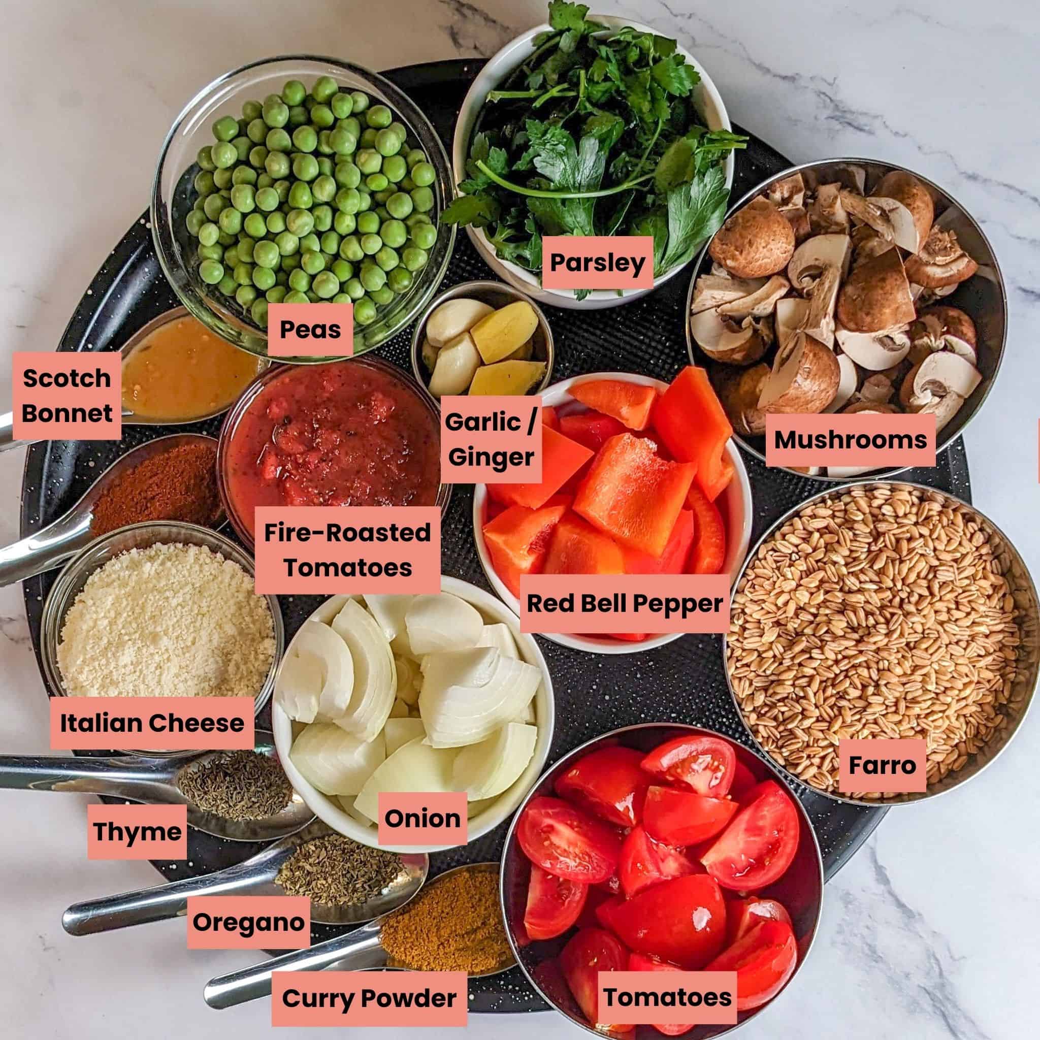 Labeled Ingredients for the Spicy Shrimp Farro Risotto with Mushrooms and Peas in glass and stainless steel containers on a large round pizza pan.