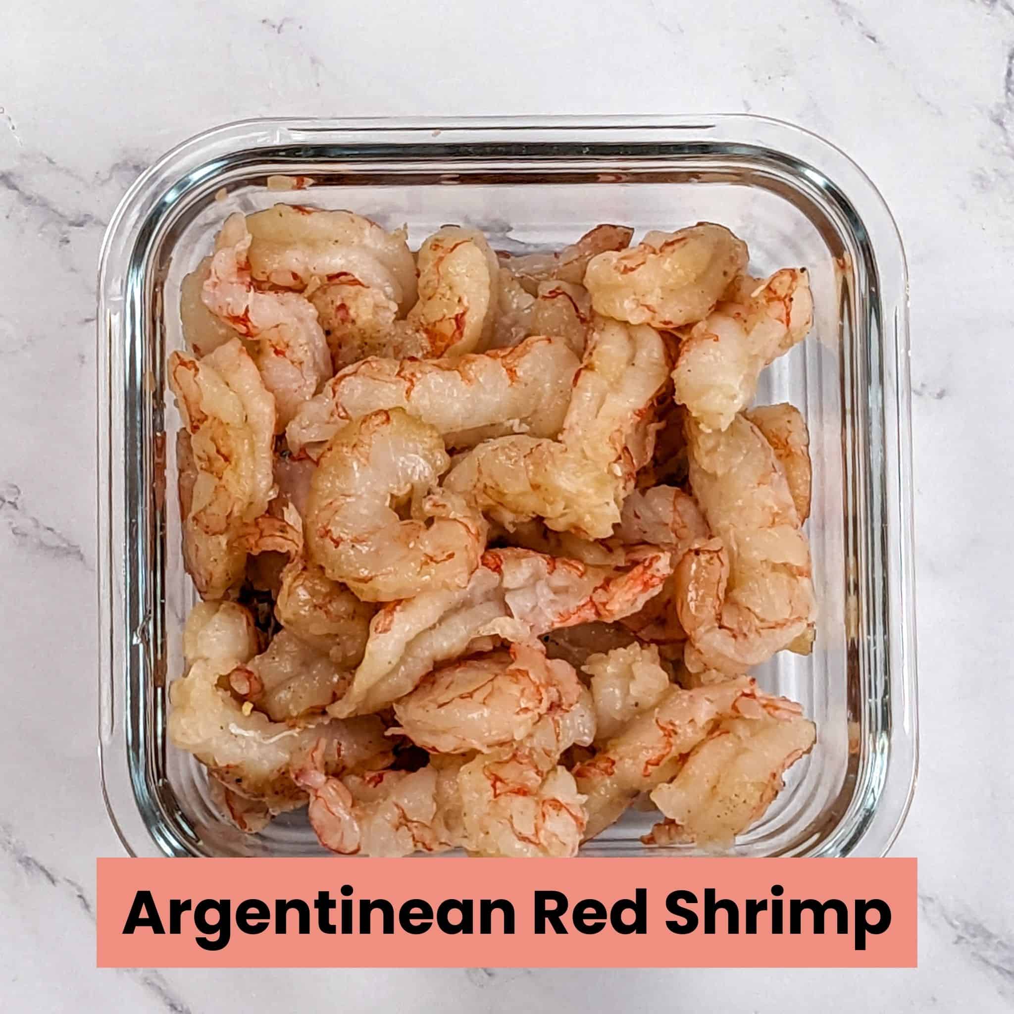raw peel deveined tail off argentinean red shrimp in a square glass container.