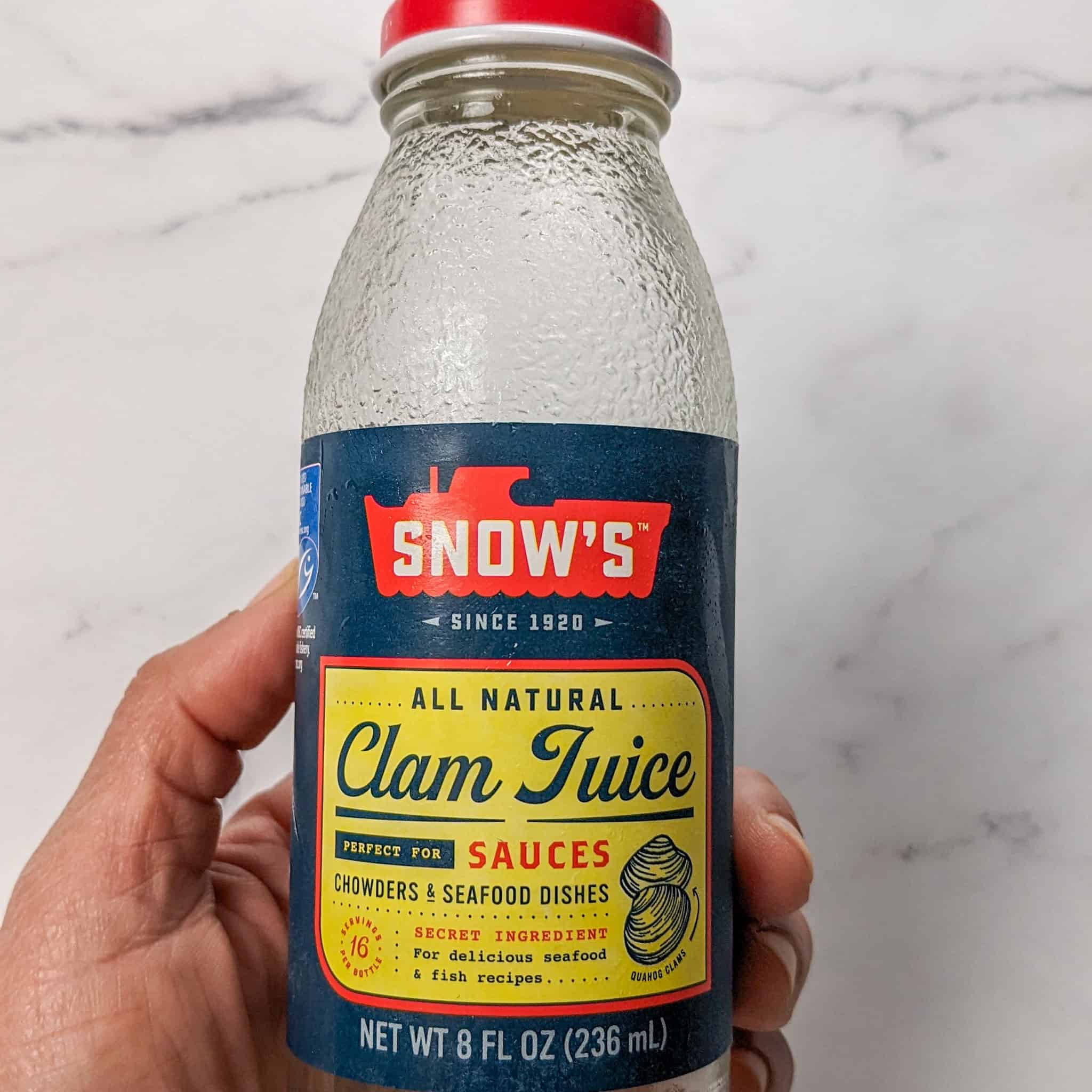 holding Snow's All Natural Clam Juice glass bottle.