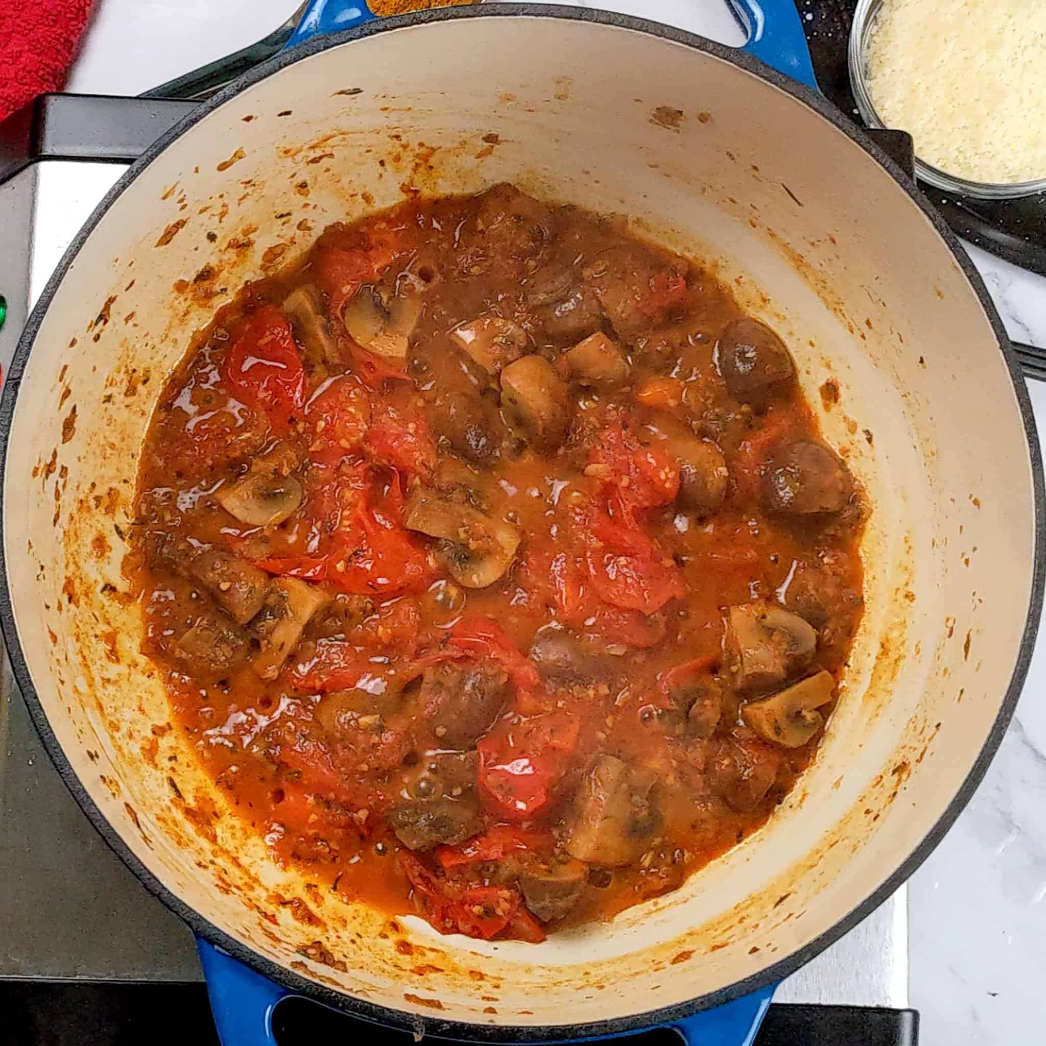 dutch oven with sauted mushrooms and cooked tomatoes.