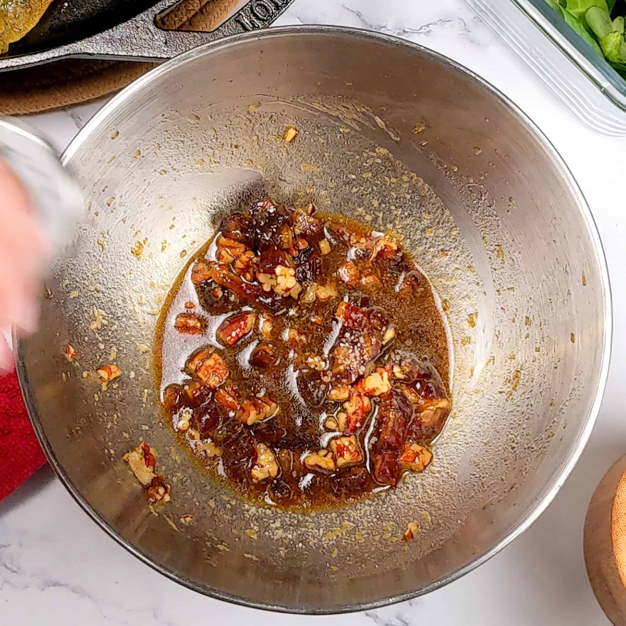 seasoning added to the pomegranate date and pecans dressing in a mixing bowl.