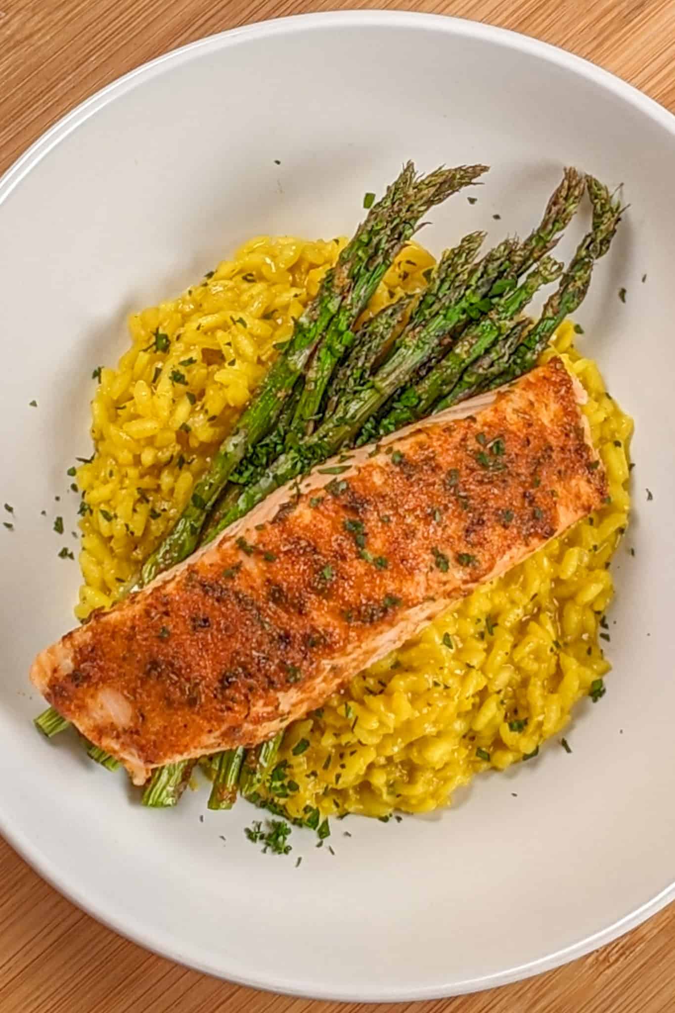 top view of the Best Air Fryer Habanero Adobo Salmon and Yellow Risotto with asparagus on a round wide rim bowl