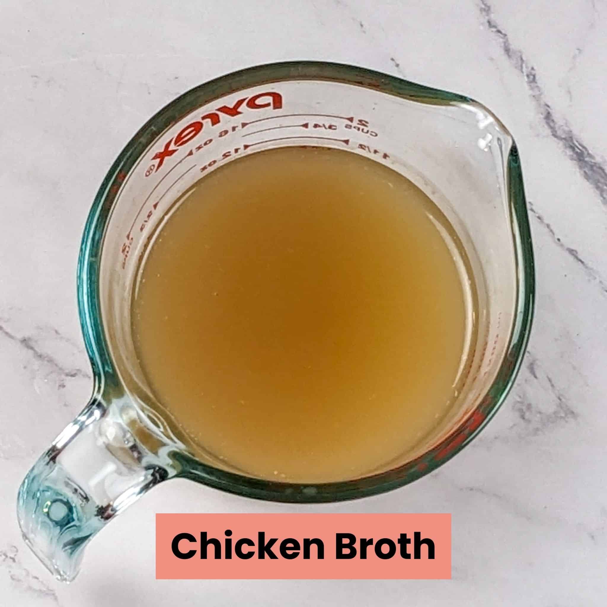 chicken broth in a glass pyrex 2-cup measuring cup.