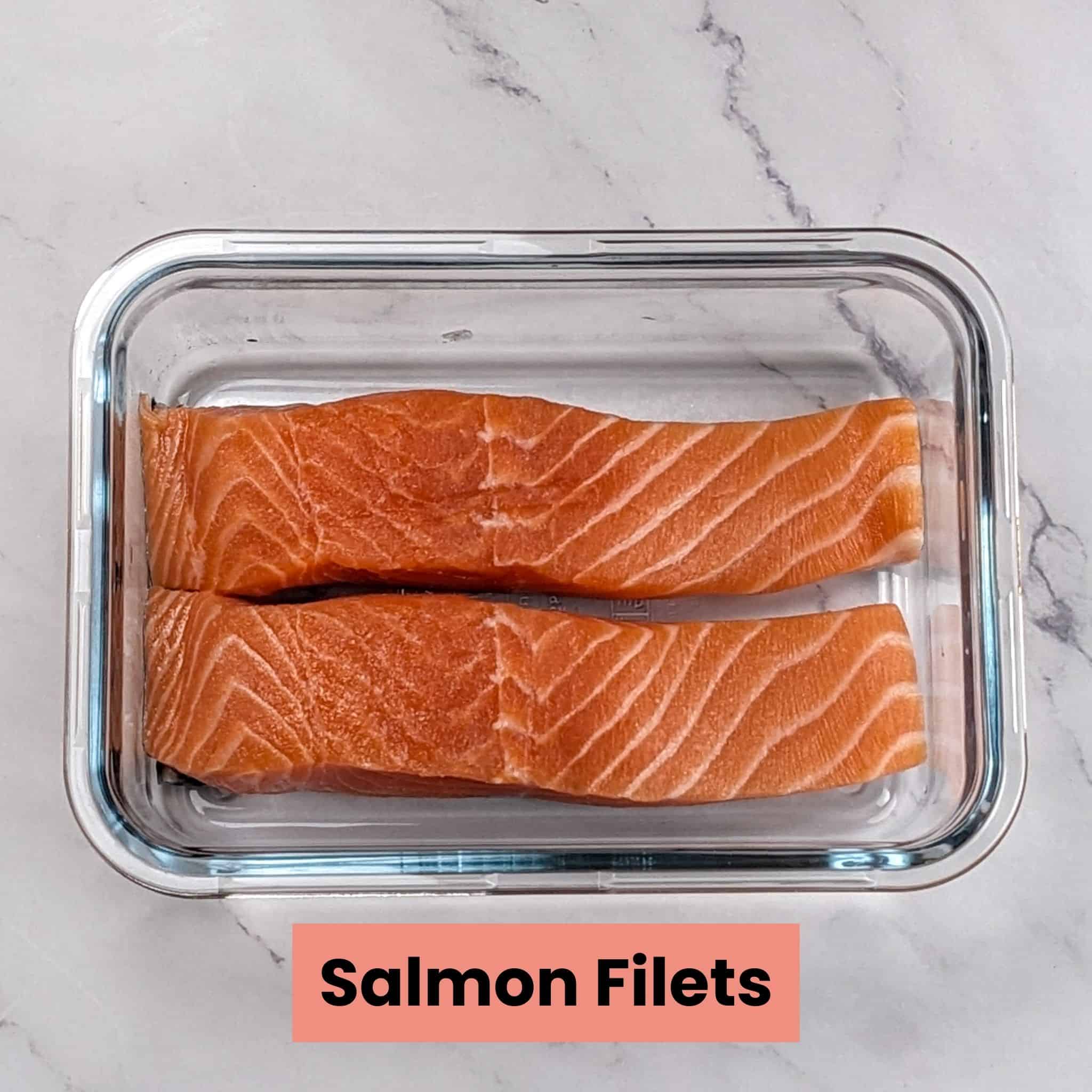 two salmon filets in a square glass shallow container.