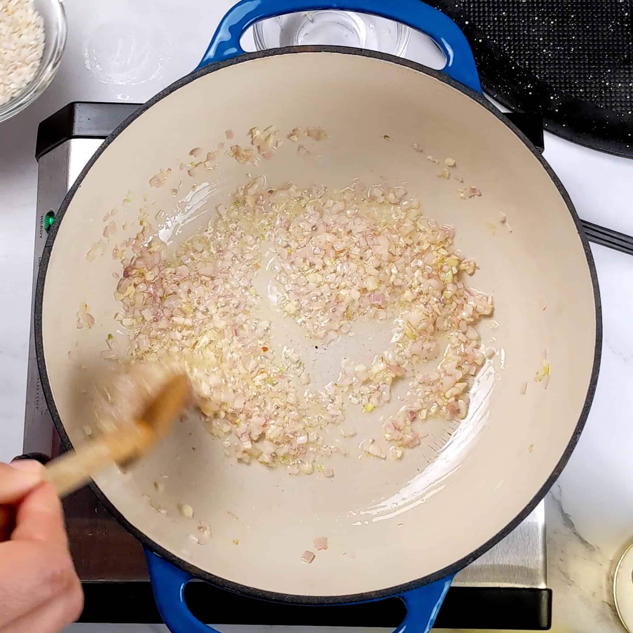 chopped shallots and garlic sauteing in a lodge enamel dutch oven.