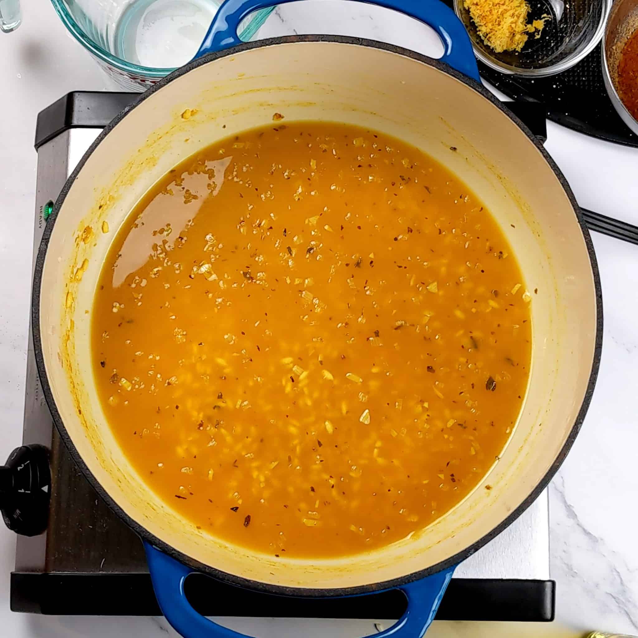 chicken broth with arborio rice in an enameled dutch oven.