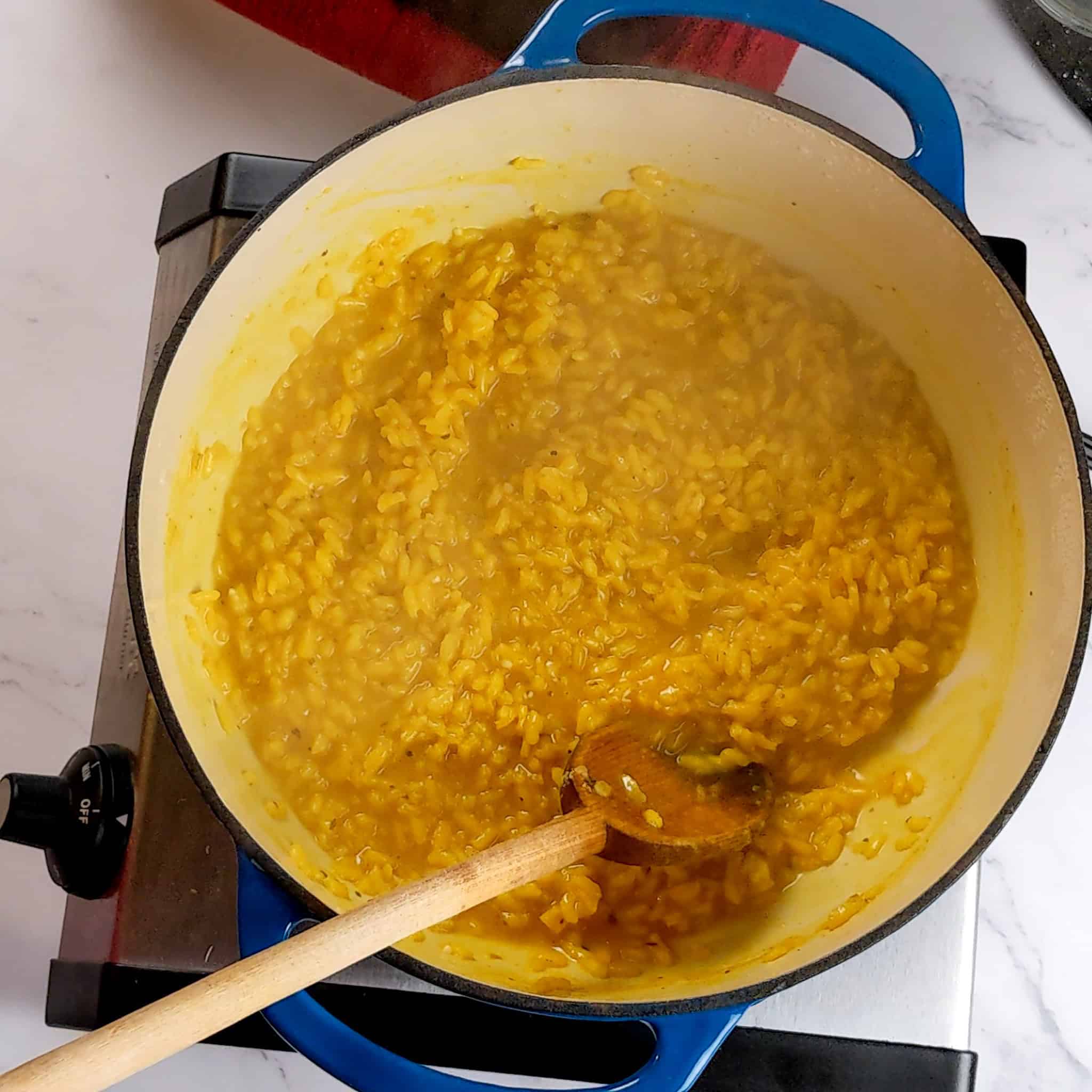 a spoon resting in the finished yellow risotto.