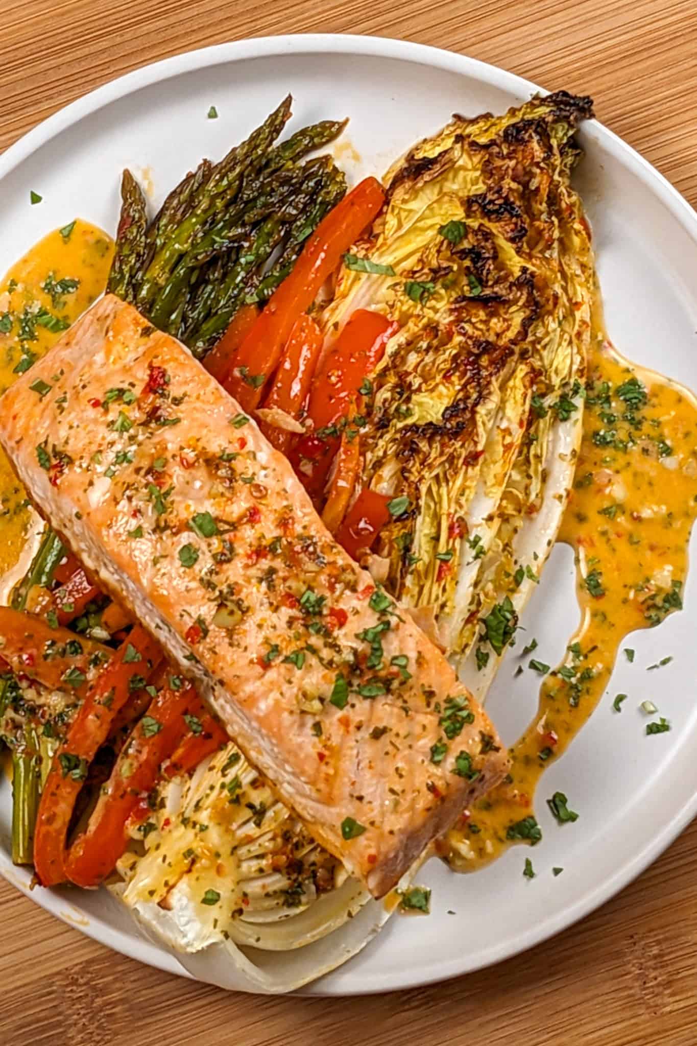 The Sheet Pan Citrus Chili Lime Salmon with Vegetables on a round flat plate with shallow sides.