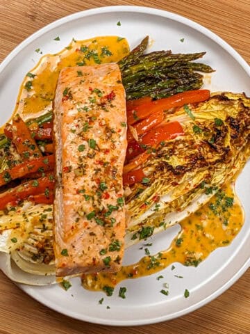 The Sheet Pan Citrus Chili Lime Salmon with Vegetables on a round flat plate with shallow sides.