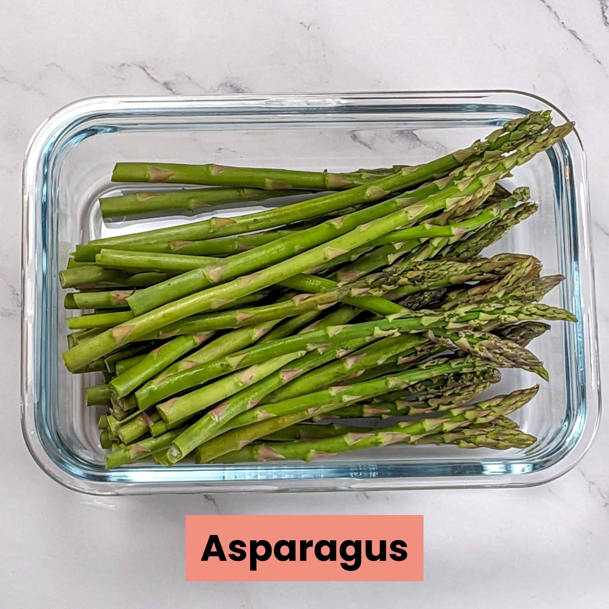 fresh raw asparagus in a glass rectangle container for the Chili Lime Salmon recipe.