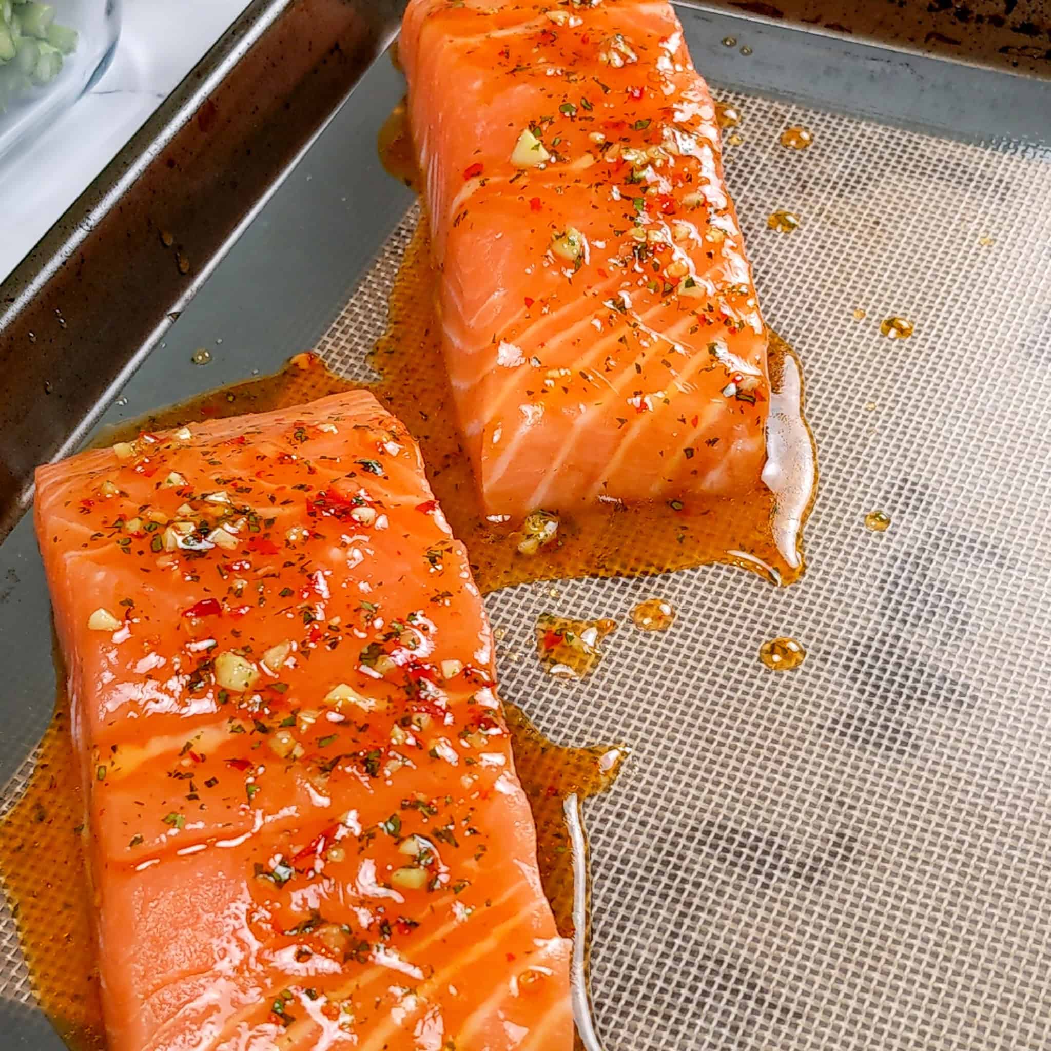 close up of the salmon on the sheet tray with the wet seasoning brushed on.