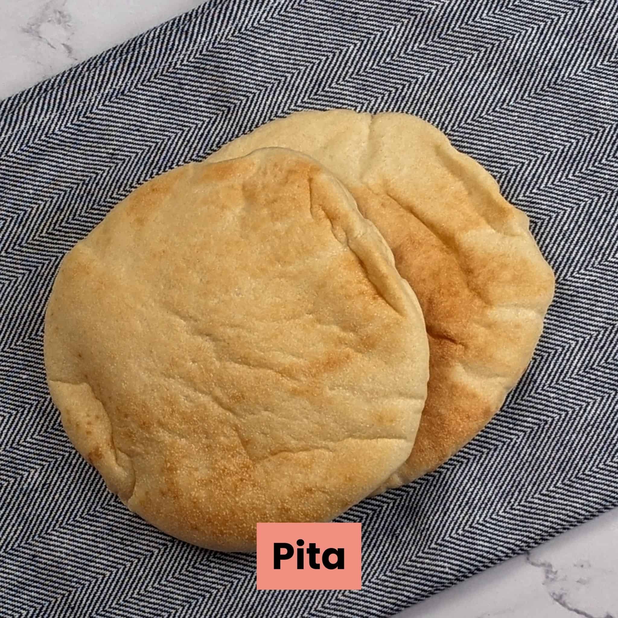 two pieces of pita bread cascading on a kitchen towel.