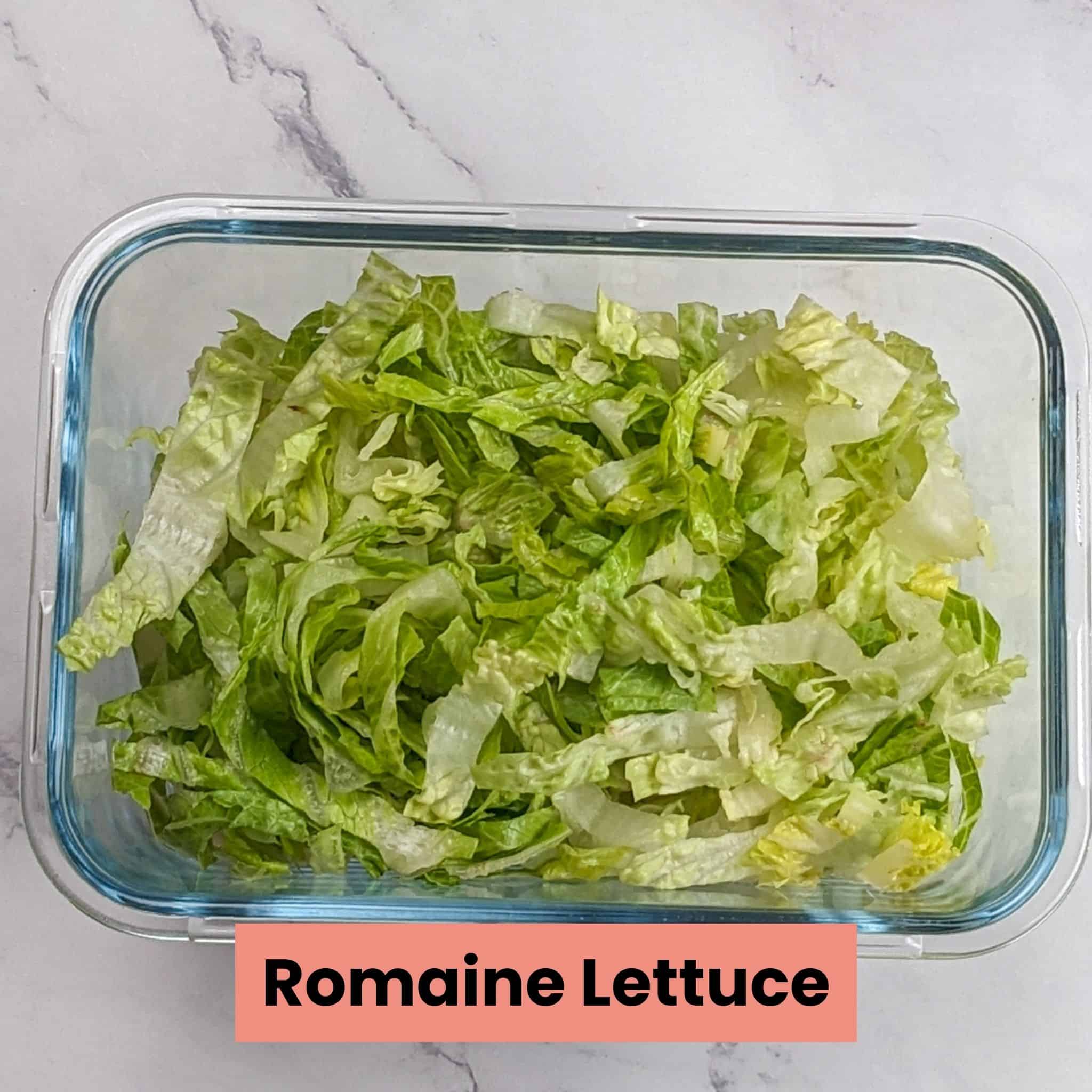 shredded romaine lettuces in a deep glass rectangle container.