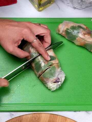 The lemongrass marinated spring roll being sliced into thirds on a color coded cutting board for ready to eat foods.