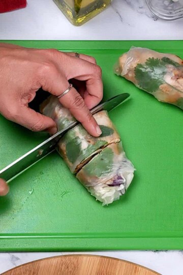 The lemongrass marinated spring roll being sliced into thirds on a color coded cutting board for ready to eat foods.