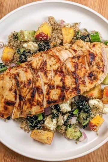 Sliced Peach Piri Piri Chicken with Fonio Kale Salad on a plate.