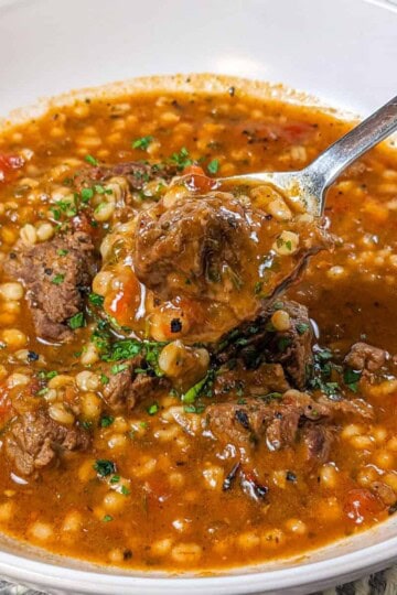 Hearty spicy beef barley stew garnished with fresh herbs, perfect for a comforting meal.