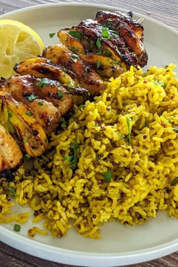 Grilled chicken skewers with yellow rice and lemon, ideal for flavorful meals or gatherings.