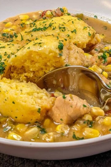 Hearty chicken corn chowder topped with fluffy cornbread dumplings and fresh parsley garnish.