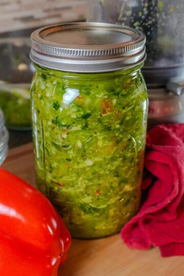 epis in a glass mason jar with kitchen equipment in the background and with whole red bell pepper laid next to it.