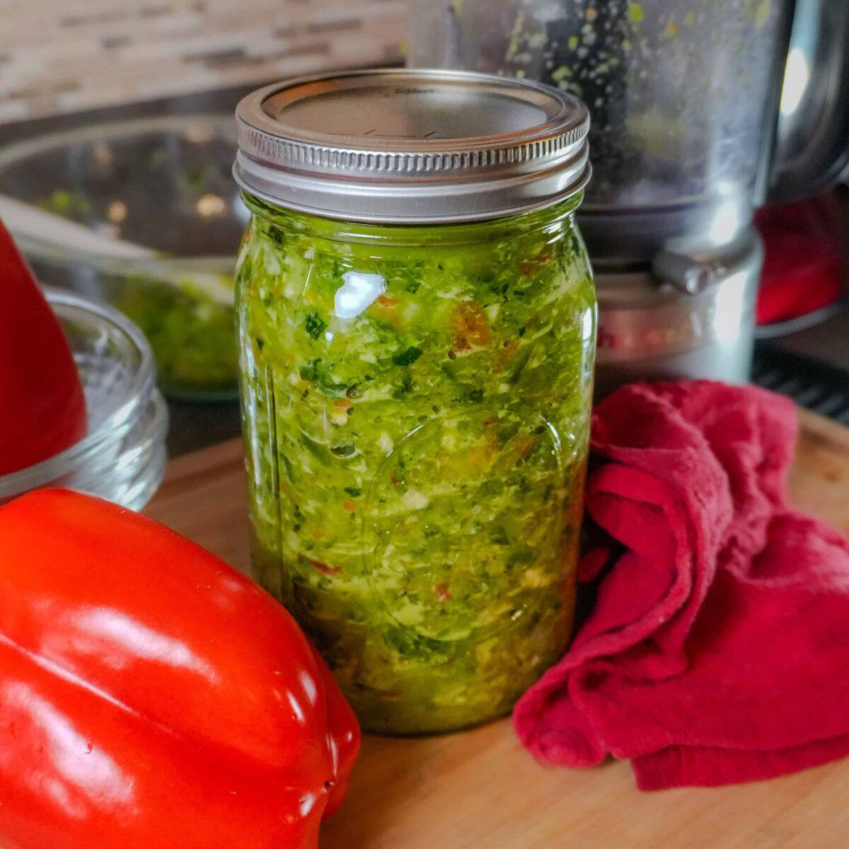 epis in a glass mason jar with kitchen equipment in the background and with whole red bell pepper laid next to it.