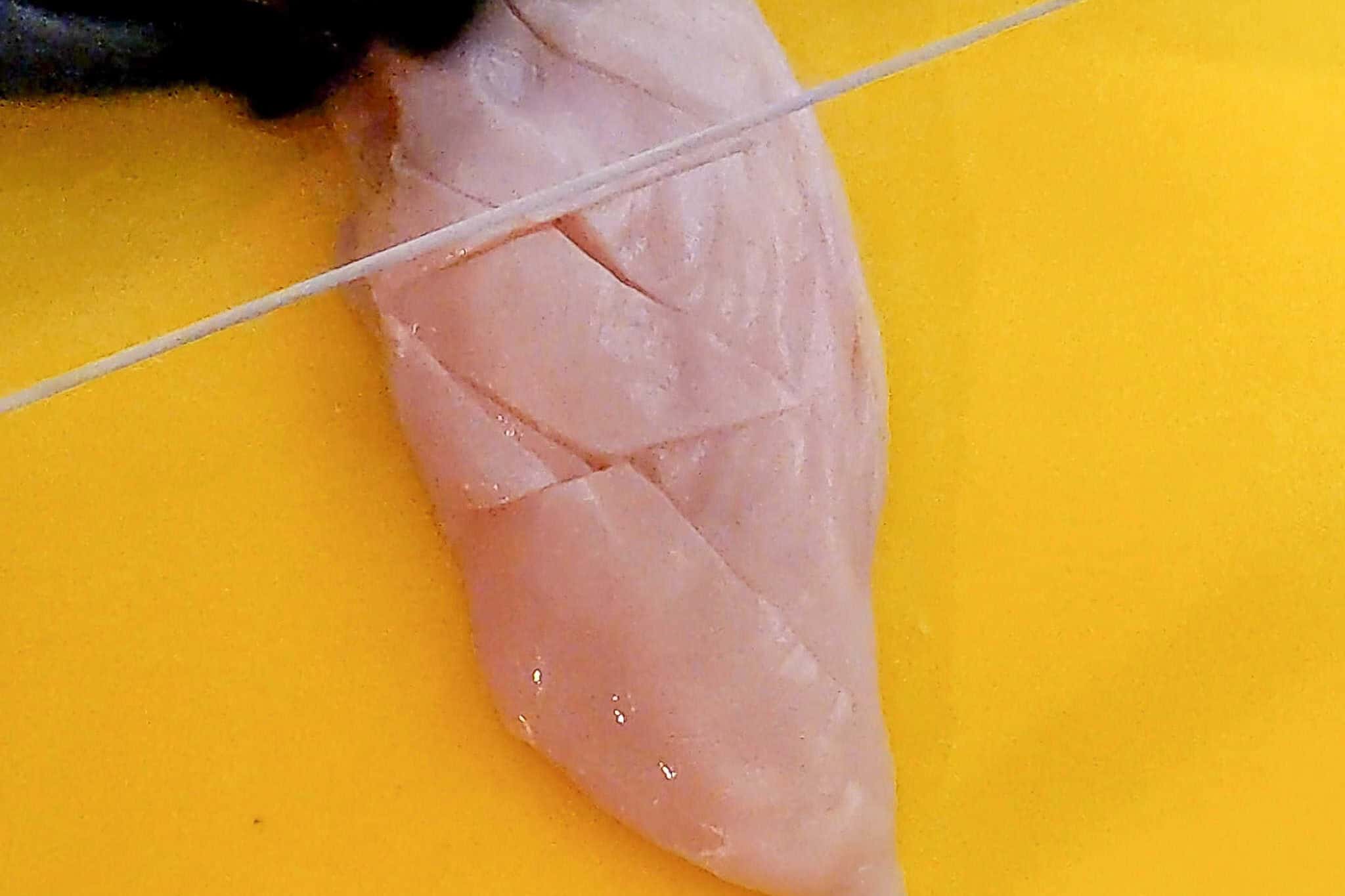 completing slitting the chicken breast on a diagonal.