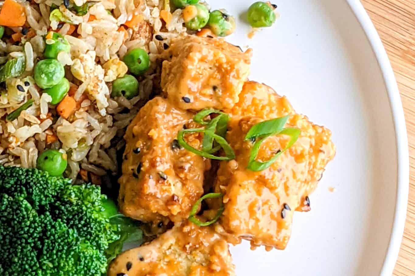 bang bang tofu with steamed broccoli and rice on a plate.