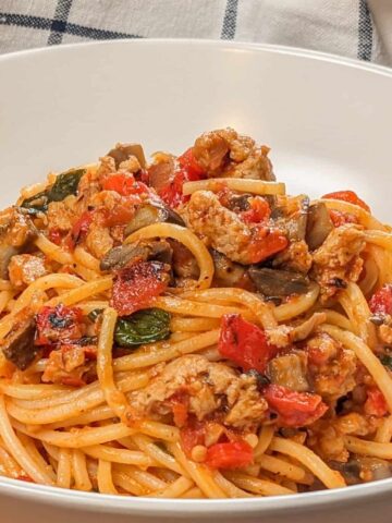 side view of the Easy Spicy Calabrian Italian Chicken Sausage Bolognese om a wide rim bowl with a kitchen t inowel the background