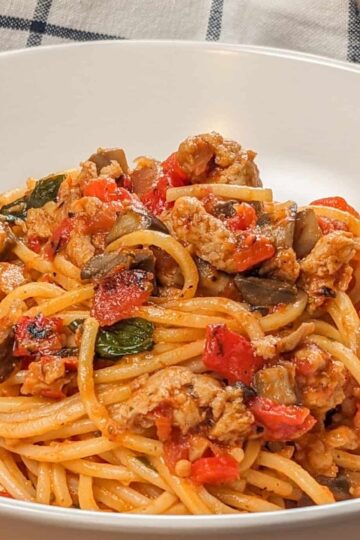 side view of the Easy Spicy Calabrian Italian Chicken Sausage Bolognese om a wide rim bowl with a kitchen t inowel the background