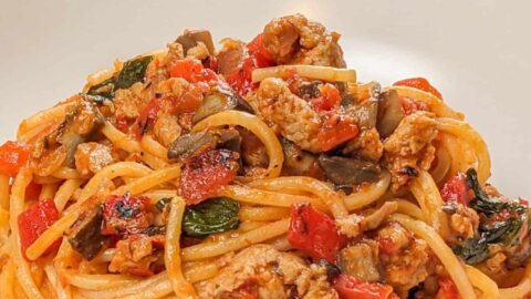 side view of the Easy Spicy Calabrian Italian Chicken Sausage Bolognese om a wide rim bowl with a kitchen t inowel the background